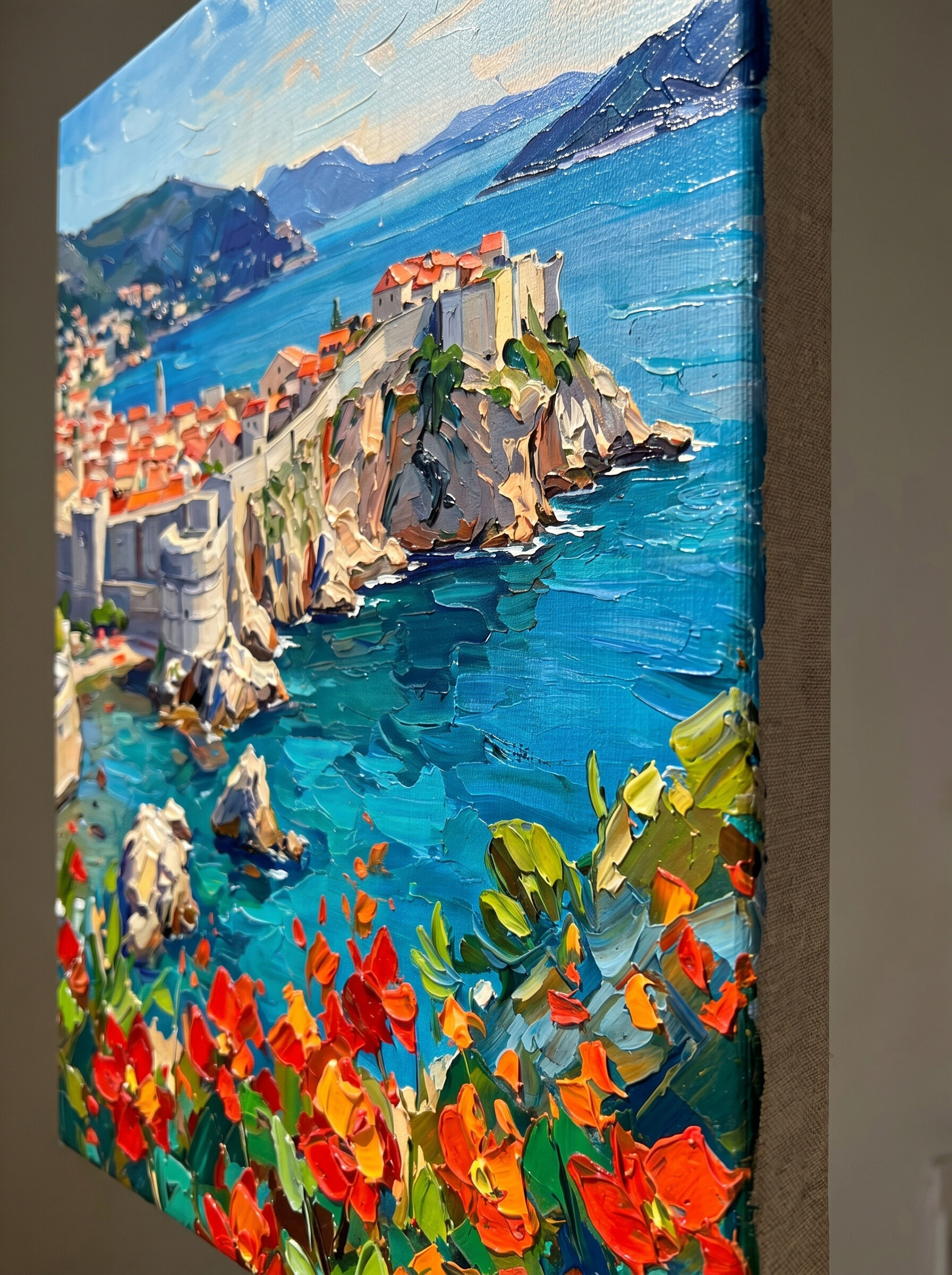 An extreme macro close-up of the "Adriatic Bloom" canvas edge. Highlighting the premium hand-embellished mixed media craftsmanship, with thick 3D palette knife impasto textures bringing the vibrant red flowers and turquoise ocean to life.